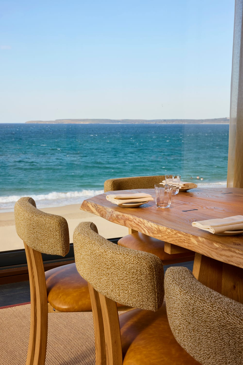 Live-edge oak table above the beach at MOR Carbis Bay